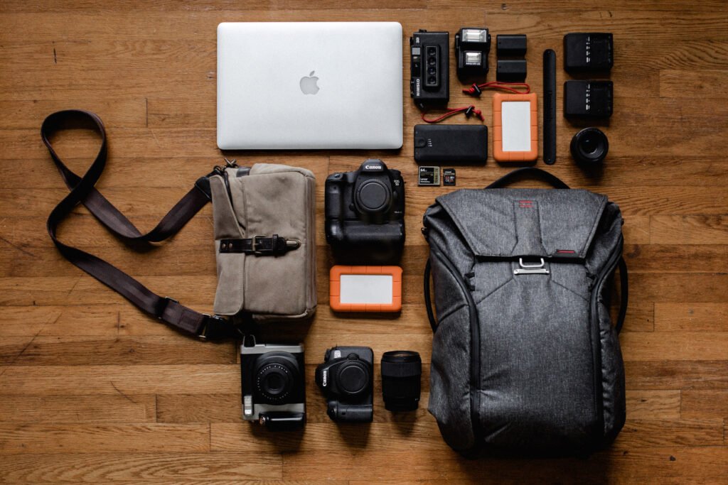 Fotoequipment-Flatlay: Rucksack in Anthrazit, Kameratasche in Khaki, Kameras und Zubehör — Legeware, Ausbildung