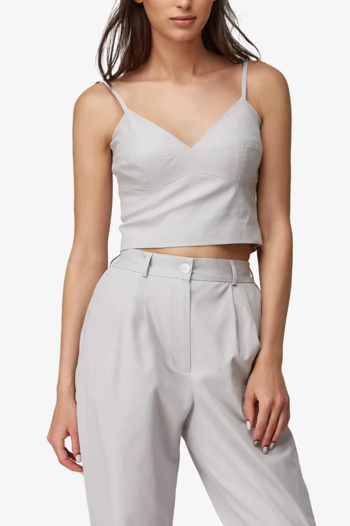Damen-Crop-Top in Hellgrau mit V-Ausschnitt und Spaghettiträgern, dazu Bundfaltenhose — On-Model-Produktfoto